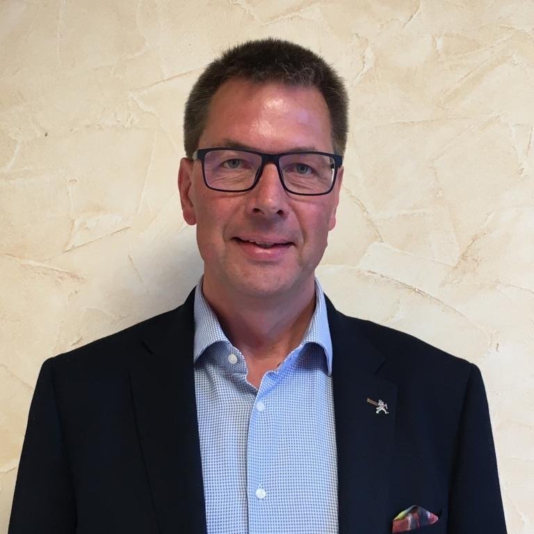 Portrait Steuerberater Dirk Sieland mit dunkelblauem Sakko und hellblauen Hemd